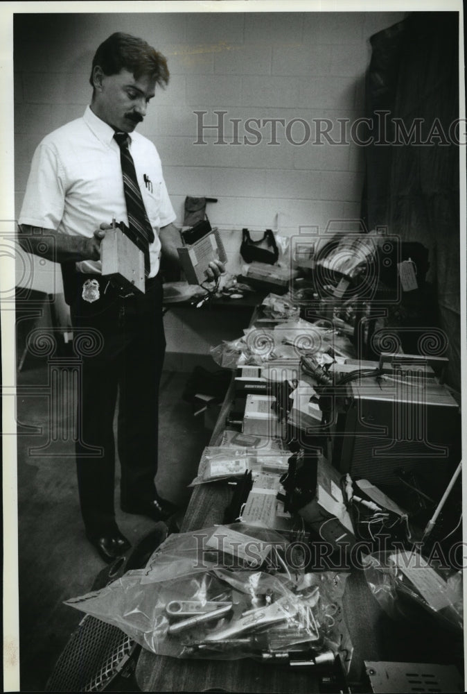 1993 Press Photo Waukesha Police Sgt. Jeff Fulwiler looks over recovered gears - Historic Images