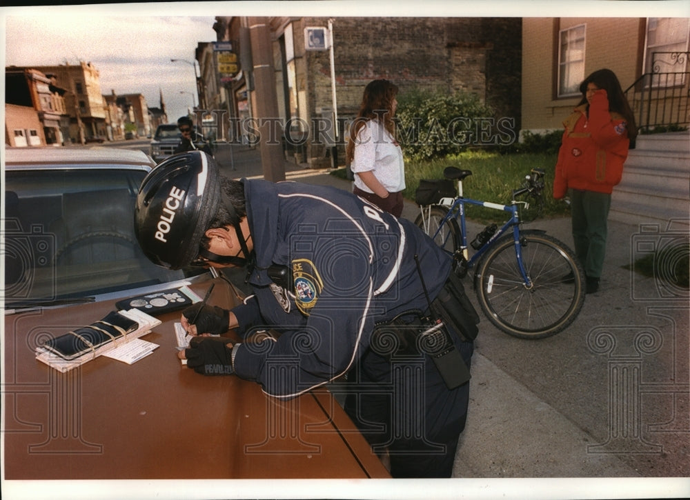 1994 Press Photo Milwaukee Officer Luis Gonzales writes a ticket to teenage girl - Historic Images