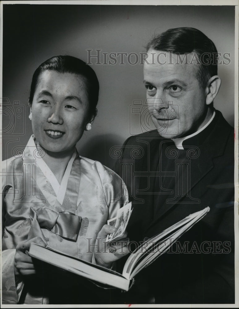 1965 Press Photo Miss Rose Kim and Father Breunig examine a book of Catholic art - Historic Images