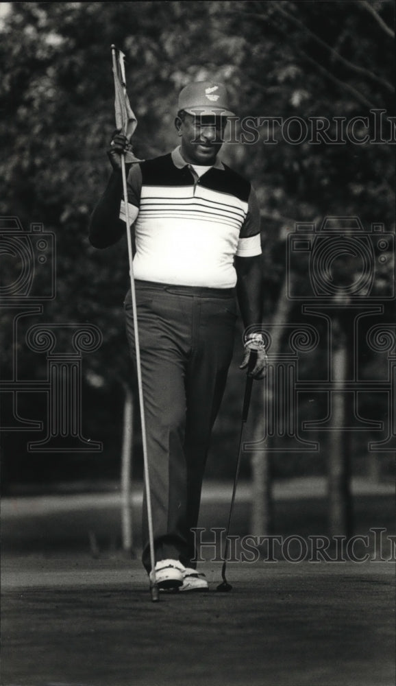 1989 Press Photo Richard E. Artison holds the flag during a morning golf outing- Historic Images