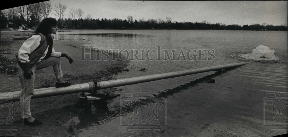 1989 Press Photo Faith Lundy checking a pipe in Pretty Lake, Wisonsin-Historic Images