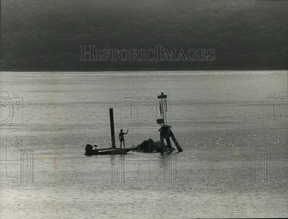 1986 Press Photo A person stands on a boat next to a buoy in disrepair - Historic Images