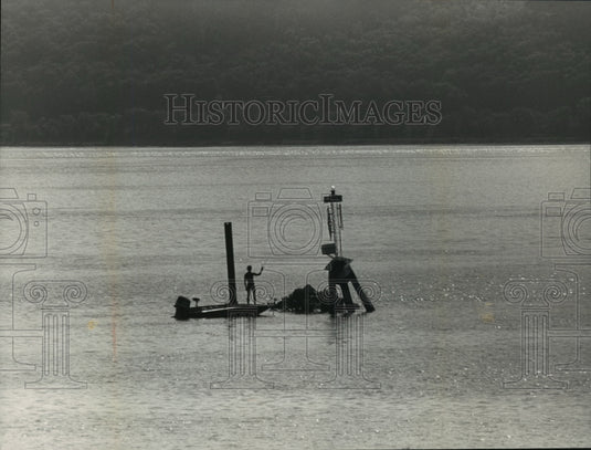 1986 Press Photo A person stands on a boat next to a buoy in disrepair - Historic Images