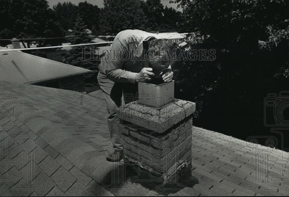 1991 Press Photo Home Inspector Jerome Baumgardt  checking a chimney atop a home - Historic Images