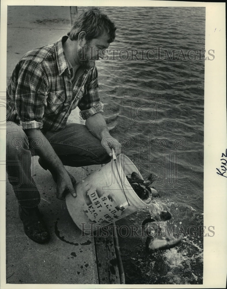 1983 Press Photo Roger Kunz, Department of Natural Resources, Stocking a Lagoon - Historic Images