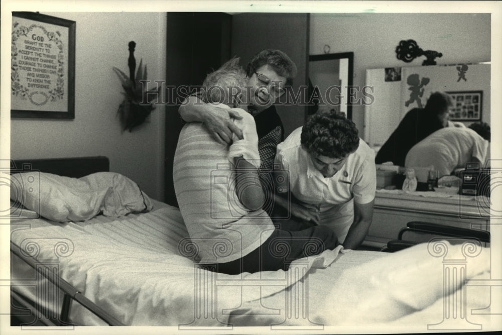 1987 Press Photo Donna Loeser and Betty Schneider Help Robert Loeser Out of Bed - Historic Images