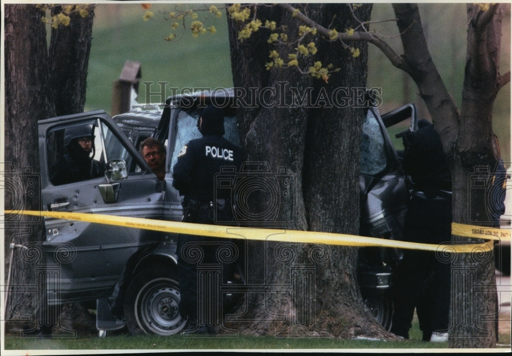 1994 Press Photo Injured suspect talks to police officer from inside trapped car-Historic Images