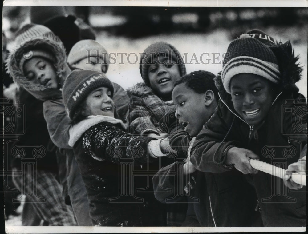 children ages 8 - 12 attending Winter Vacation Camp play tug-of-war-Historic Images