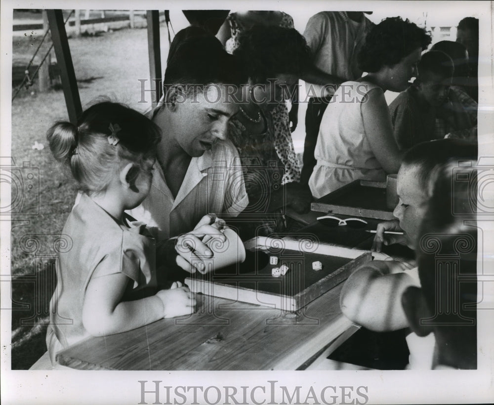 1962 Press Photo Girl Watches Her Father Play Dice To Raise Money - mja87093- Historic Images