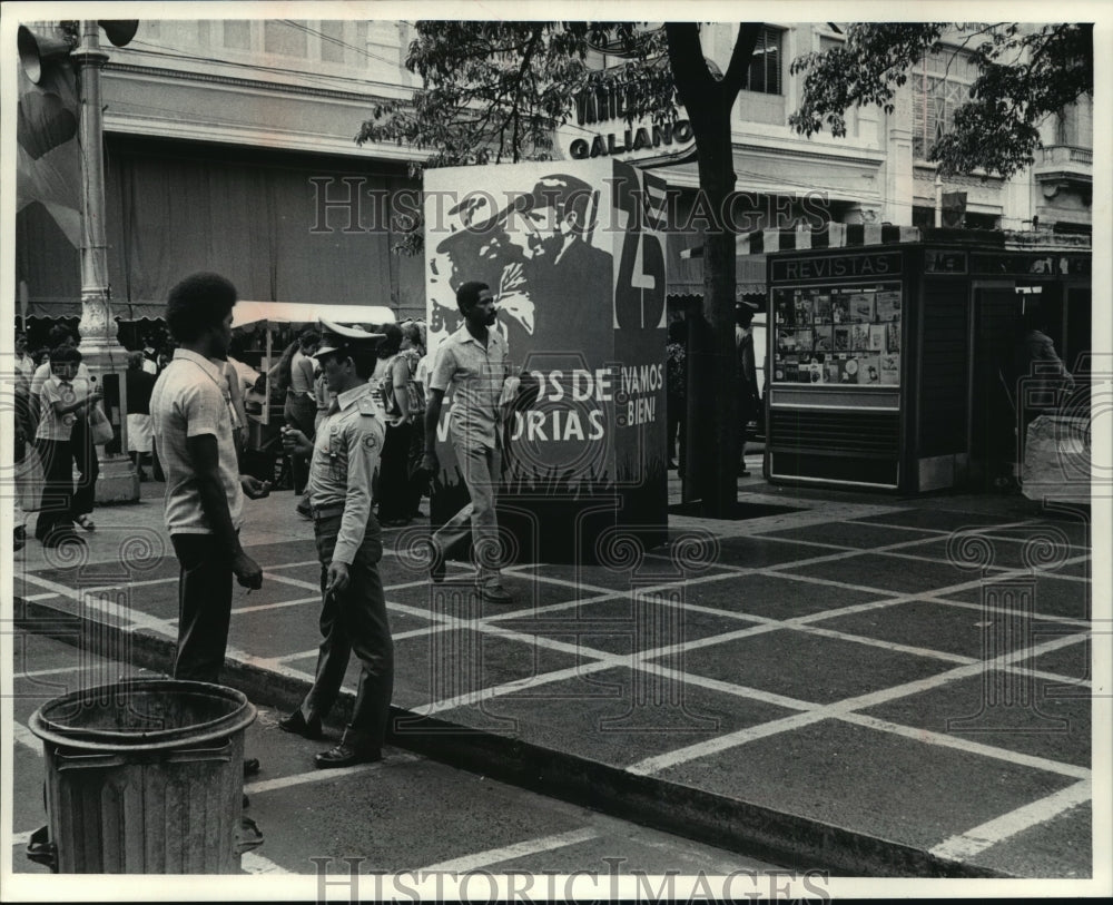 1984 Press Photo Havana shoppers stroll past poster celebrating Cubas revolution - Historic Images