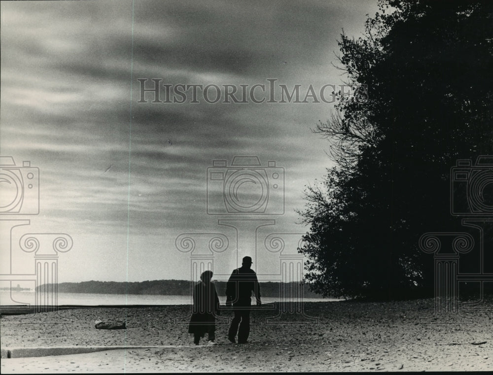 1988 Press Photo Two figures walking along shores at Doctors Park beach - Historic Images