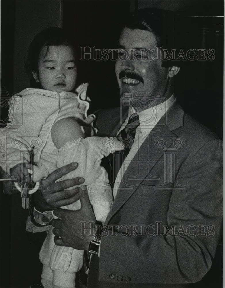 1985 John Eckl carried his newly adopted daughter off the plane - Historic Images