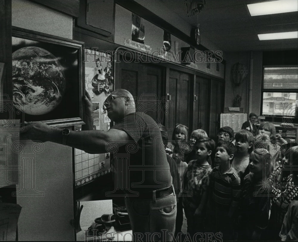 1990 Students watch as Ed Gerstmann hangs a photo of the earth - Historic Images