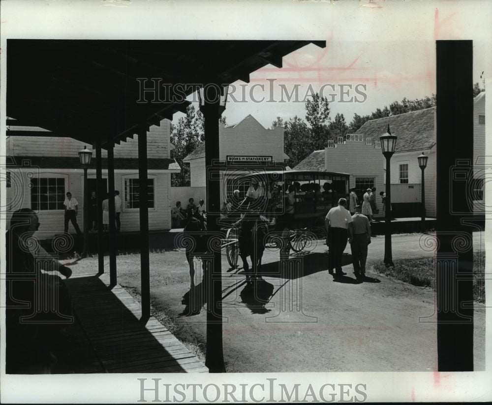 1964 Crowd traffic in village square at Stonefield - Historic Images