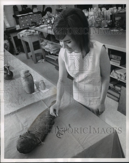 1966 Press Photo Mary Haaya of the museum staff examines a baby mummy - Historic Images