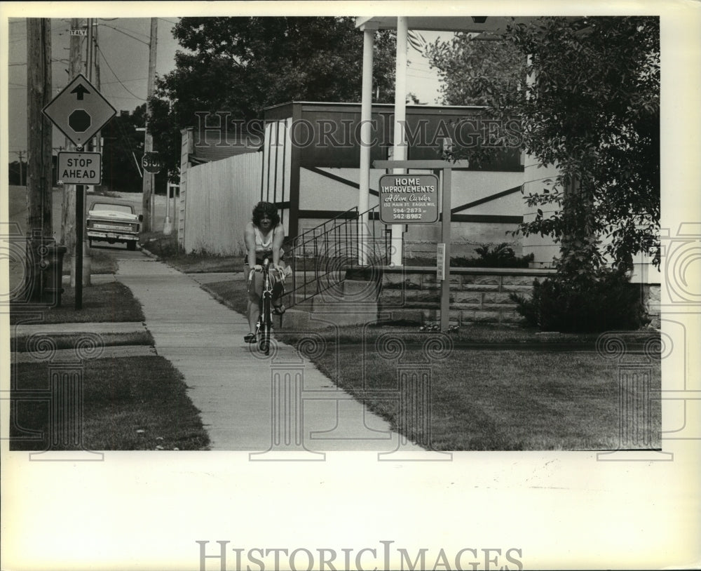 1981 Press Photo Woman Rides Bike Down Eagle, Wisconsin Sidewalk - mja98562 - Historic Images