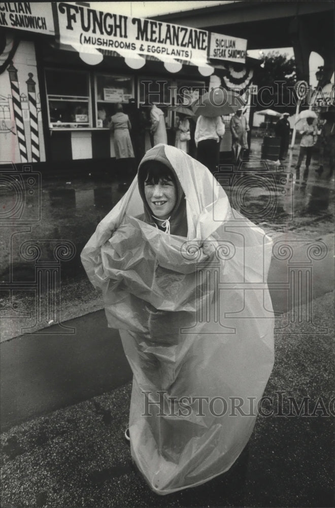 1980 Press Photo Judd Shultz uses a trash bag to protect himself from rain - Historic Images