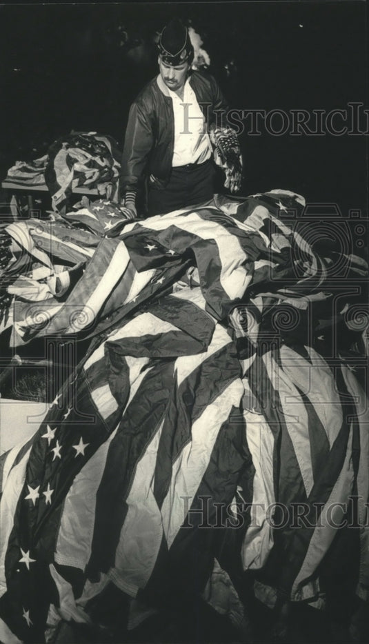 1986 Press Photo Tracy Roy of Grafton Looked Over A Pile of Flags - mjb11315 - Historic Images