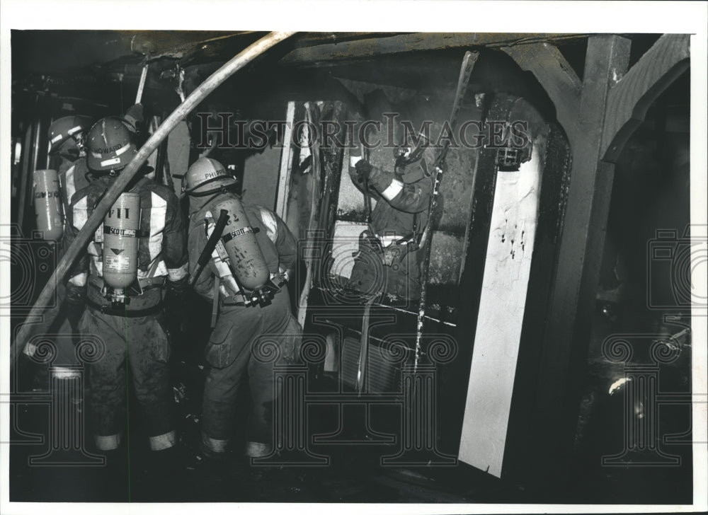 1991 Press Photo Waukesha firefighter Steve Timm uses ax on motel fire - Historic Images