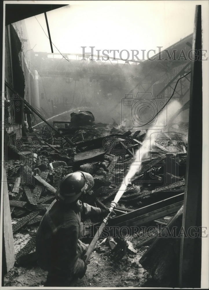 1988 Press Photo Firefighter sprays rubble at destroyed Park Theater, Wisconsin - Historic Images