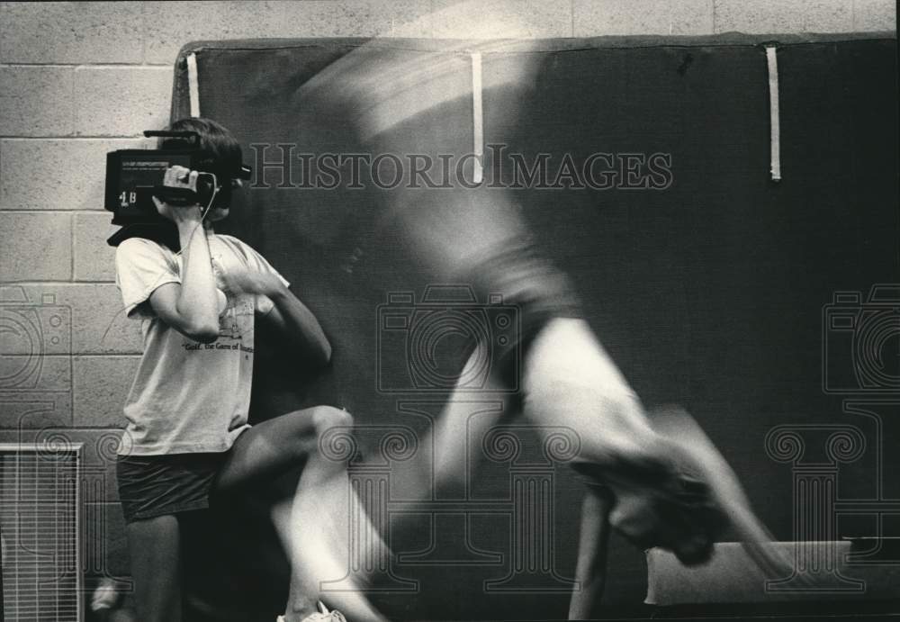 1986 Press Photo Tom Gondek tapes a whirling gymnast, Greendale High, Wisconsin. - Historic Images