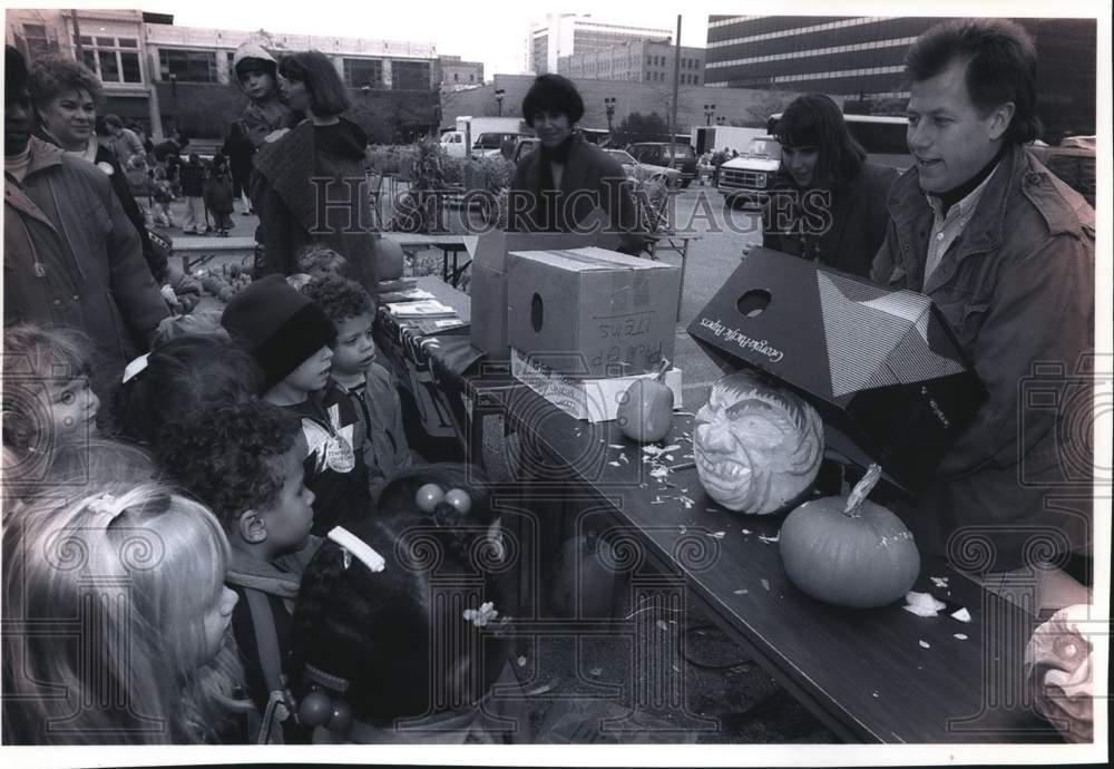 1993 Press Photo Man shows carved pumpkin to children at Green Market, Wisconsin - Historic Images