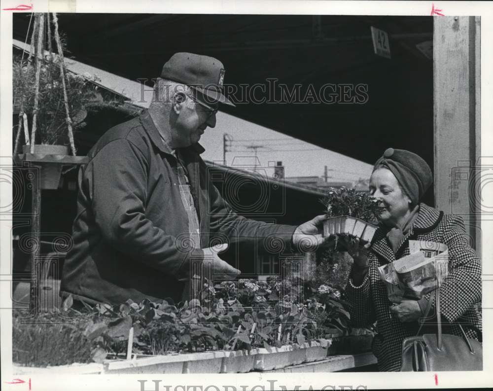 1975 Woman smells flowers at James Swan&#39;s booth, West Allis market - Historic Images