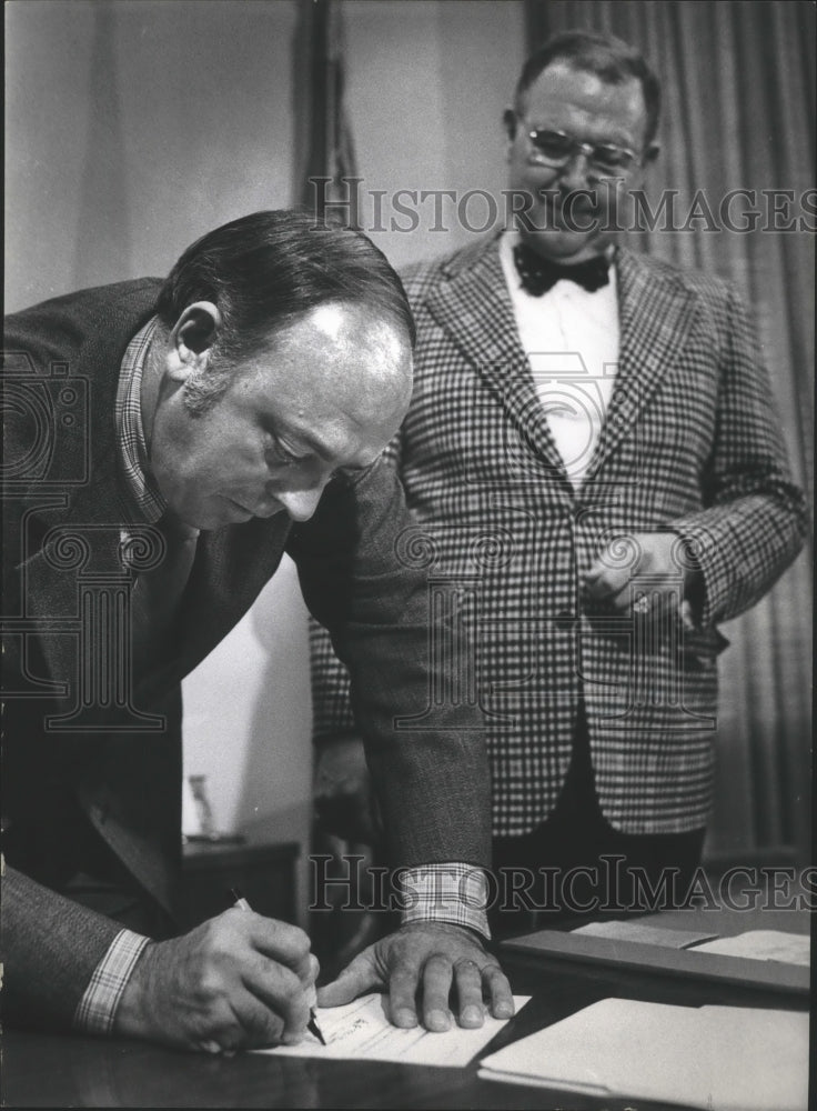 1975 Press Photo Lee McMurrin signs a document for a man in Milwaukee, Wisconsin - Historic Images