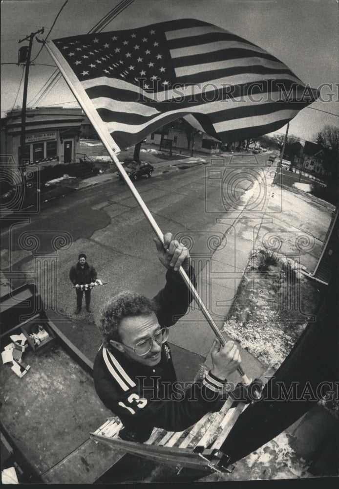 1991 Press Photo Greg Sieber watches Mr. Heft install a flag on Main, Wisconsin. - Historic Images