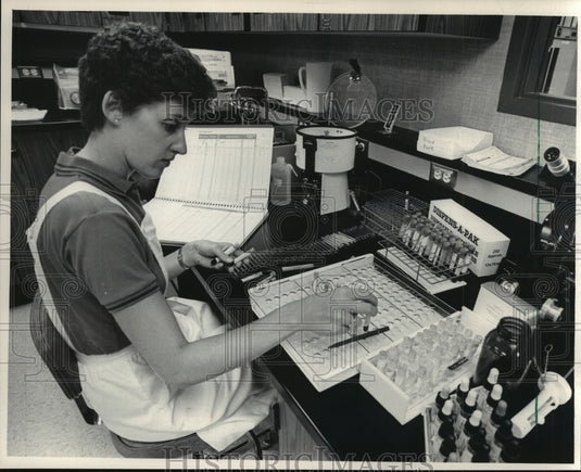 1985 Press Photo Sue Weirather separates urine samples at health center - Historic Images
