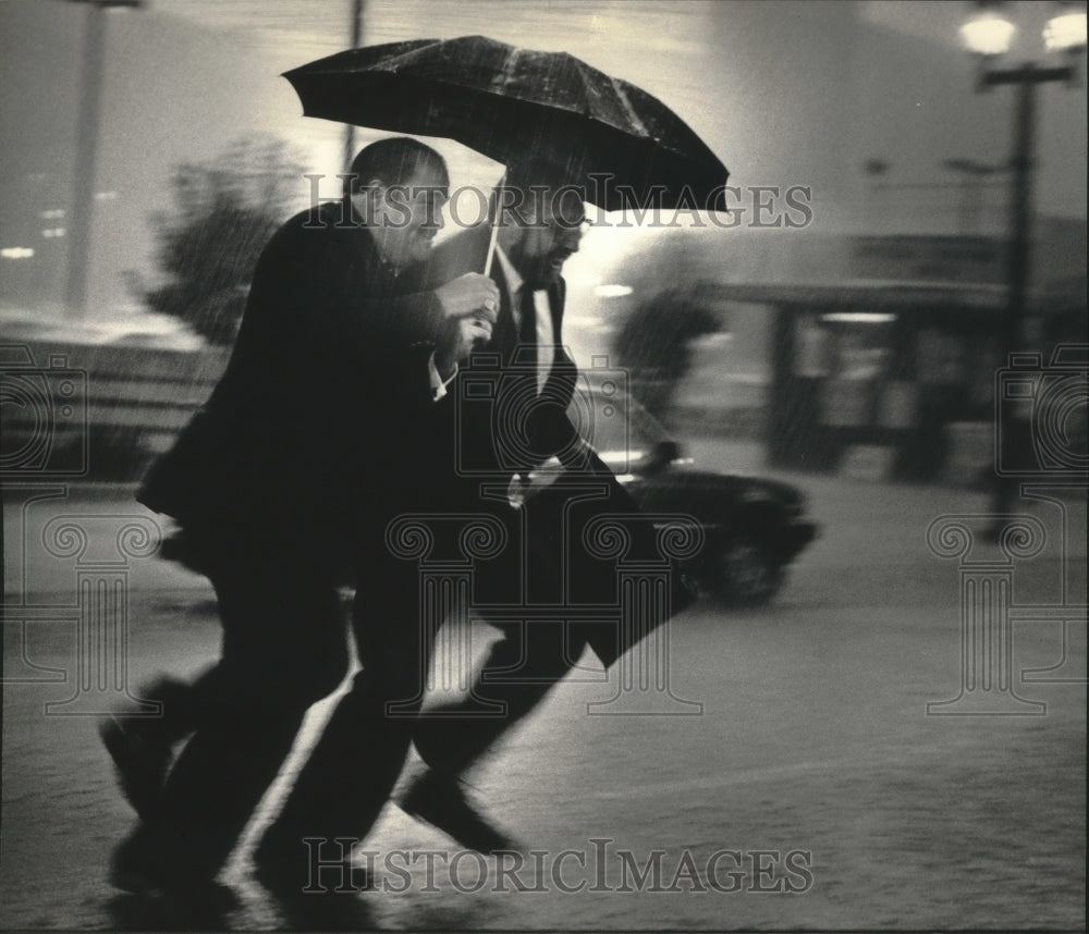 1986 Press Photo Two men run in the rain near Grand Avenue, Milwaukee, Wisconsin - Historic Images