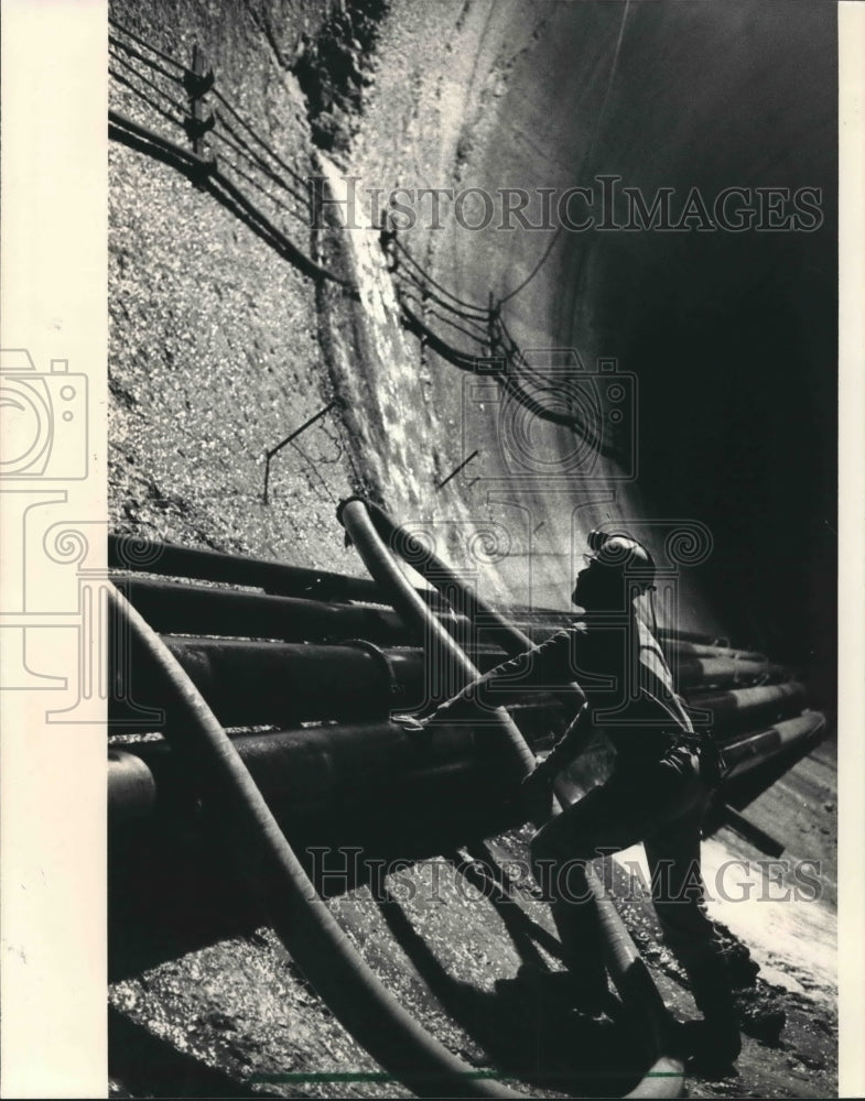 1987 Press Photo Worker adjusts hose as ground water pours through tunnel wall - Historic Images