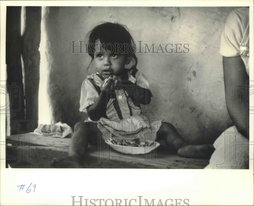 1987 Press Photo Little girl enjoys bowl of fruit in her Honduran house - Historic Images
