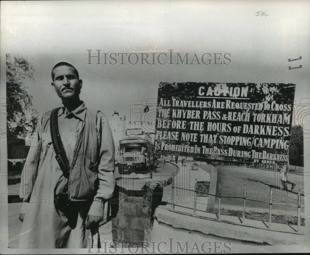 1977 Press Photo A policeman stood near a warning sign at Khyber Pass, Pakistan - Historic Images