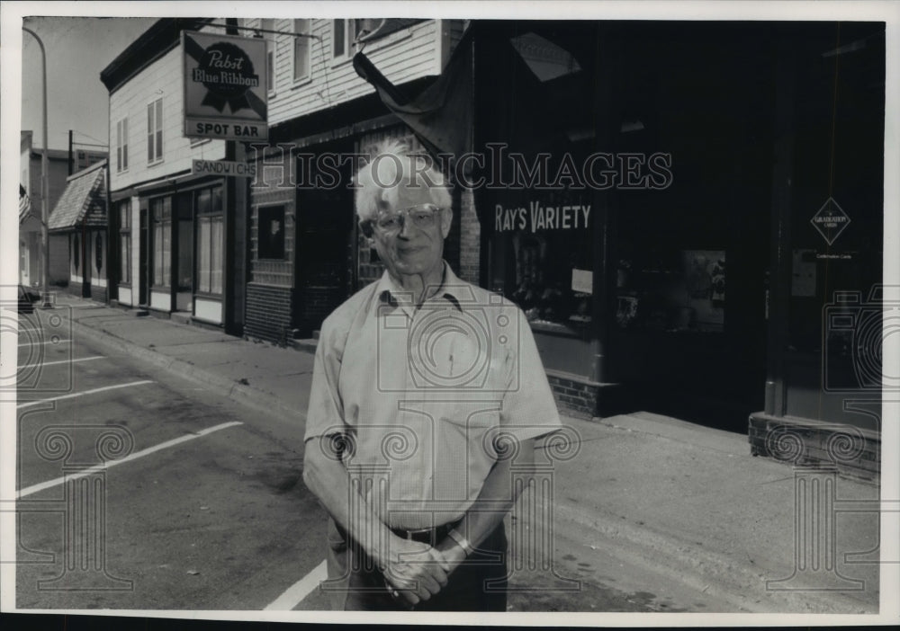 1988 Press Photo Ray Cozemius Stands in front of his store in Owen, Wisconsin. - Historic Images