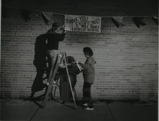 1994 Press Photo Dennis Brand, Dian Fritsch hang banner in Holy Family School - Historic Images