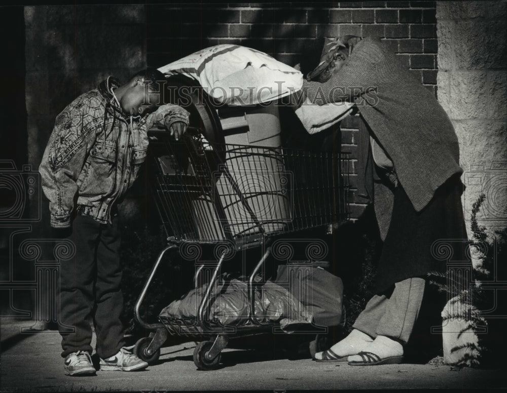 1989 Press Photo Anna Norwood and son, slumped over belongings waiting for help. - Historic Images