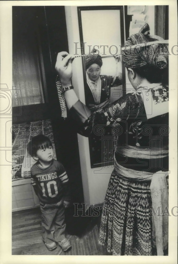 1985 Press Photo Tou Tseem Dang Her, 5 watches his mother dress ( Hmong) - Historic Images
