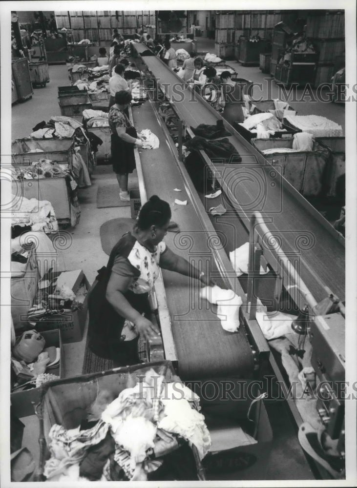 1989 Employees of Goodwill Industries sort clothing at headquarters - Historic Images