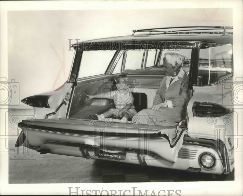 1959 Press Photo Woman and a child sit in the back of an 1960 Oldsmobile Fiesta - Historic Images