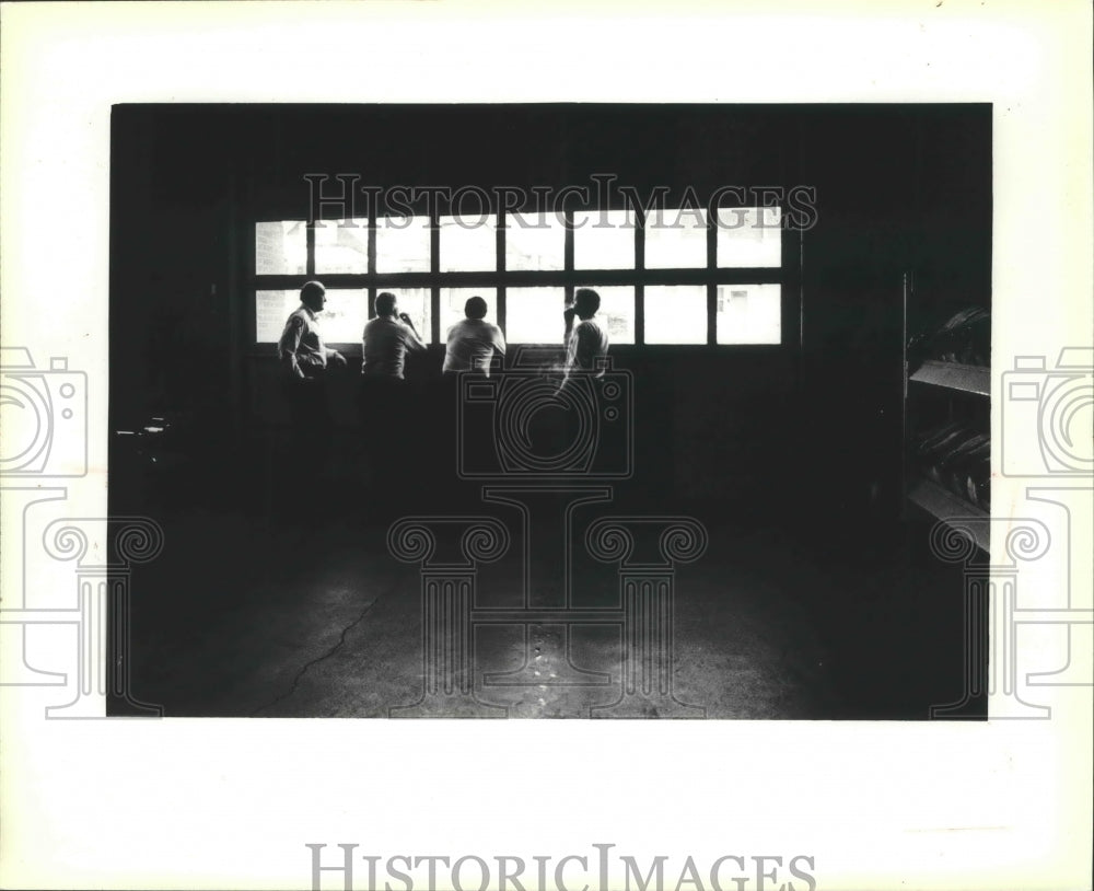 1979 Milwaukee fire fighters looking out window of overhead door. - Historic Images