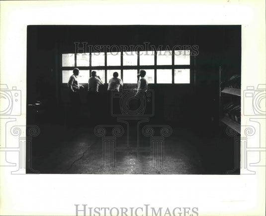 1979 Milwaukee fire fighters looking out window of overhead door. - Historic Images