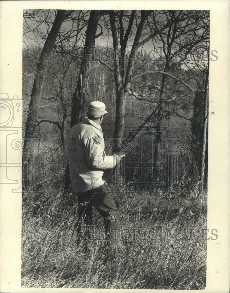 1986 Deer hunter watching a wooded draw in Wisconsin - Historic Images