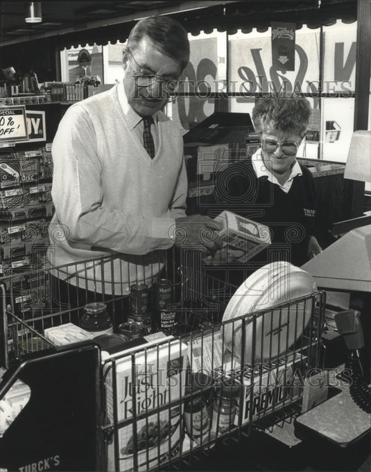 1990 Oner helped employee ring up groceries at Turck's Food Fare - Historic Images
