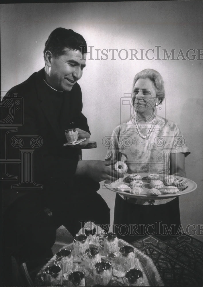 1964 Press Photo Father Nasser offered traditional cookies by Mrs. James Arrieh.-Historic Images
