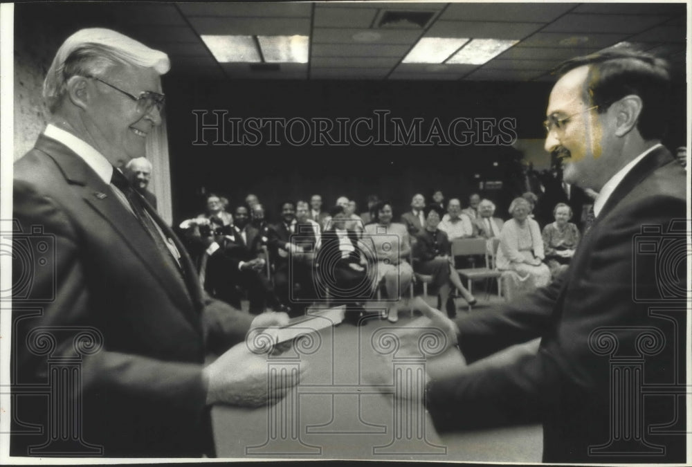 1992 W. Martin Morics (right) and James A. McCann are trading gifts. - Historic Images