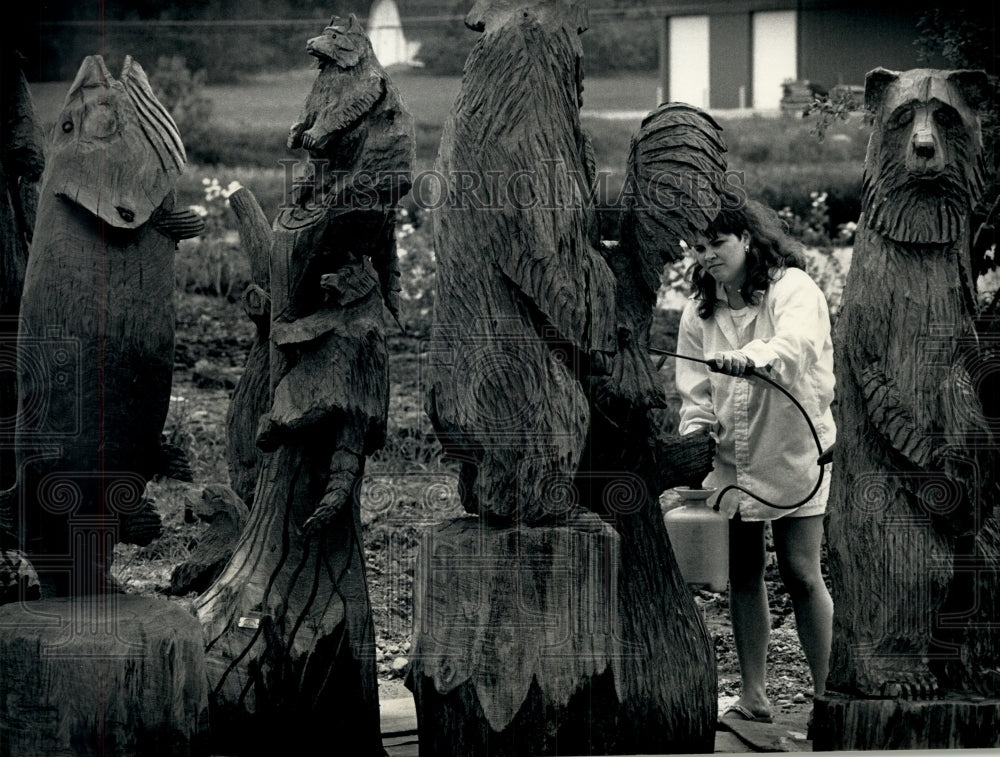 1991 Press Photo Tammy Jensen applies preservative to husband Larry&#39;s sculptures - Historic Images