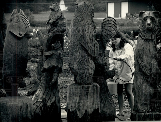 1991 Press Photo Tammy Jensen applies preservative to husband Larry's sculptures - Historic Images