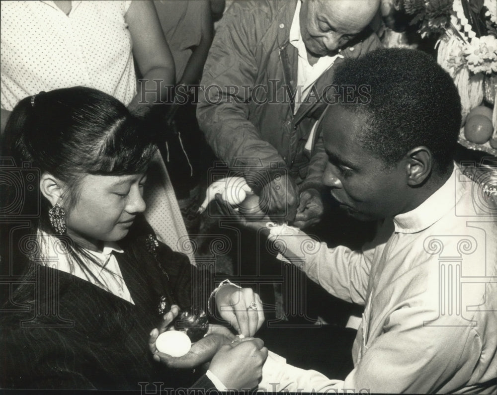 1989 Lou Lo gives Father Francis Kariuki a prayer bracelet - Historic Images