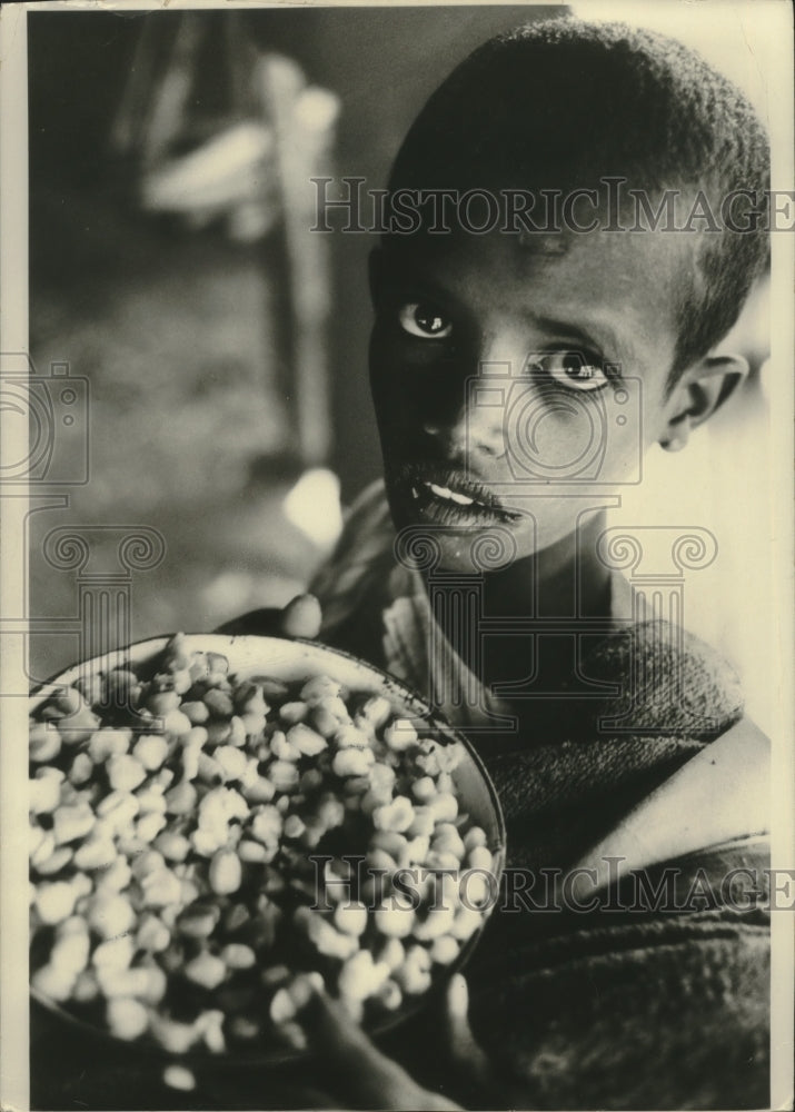 1974 Press Photo A hungry child in Ethiopia holds a precious bowl of grain - Historic Images